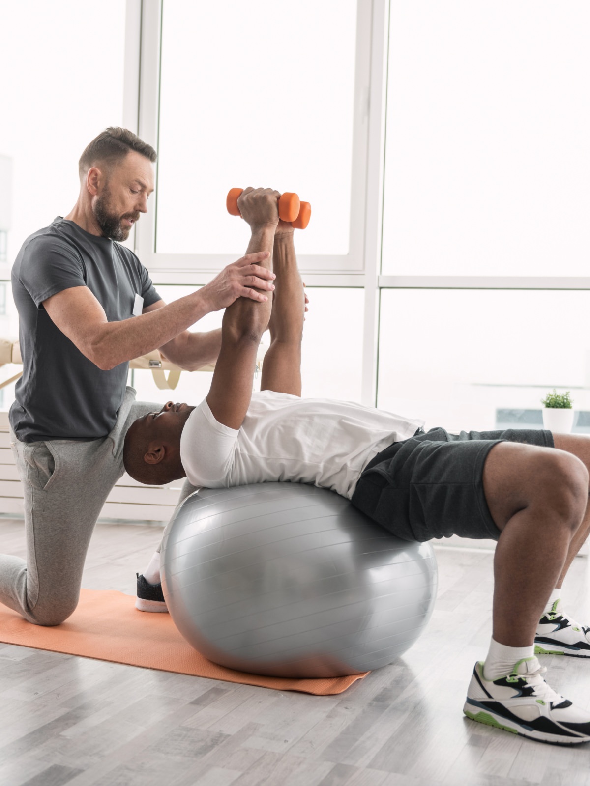 personal trainer working with a man on a yoga ball
